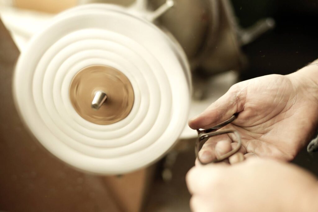 Handwerker beim Polieren einer Hornbrille, hervorhebend die Handwerkskunst und Präzision in der Brillenfertigung.