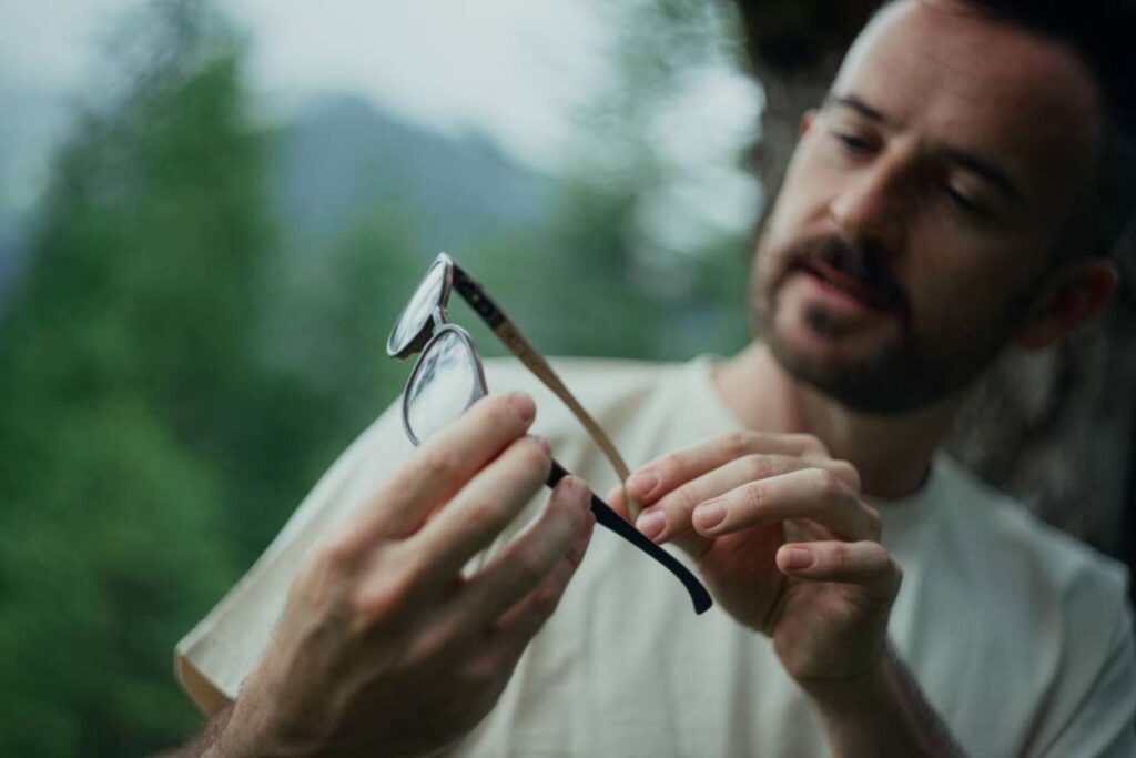 Man examining eco glasses carefully, a symbol of sustainable living